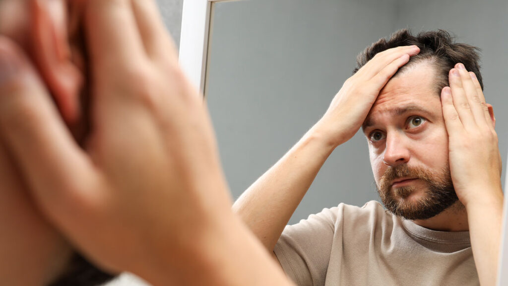 Hombre revisando su cabello frente al espejo